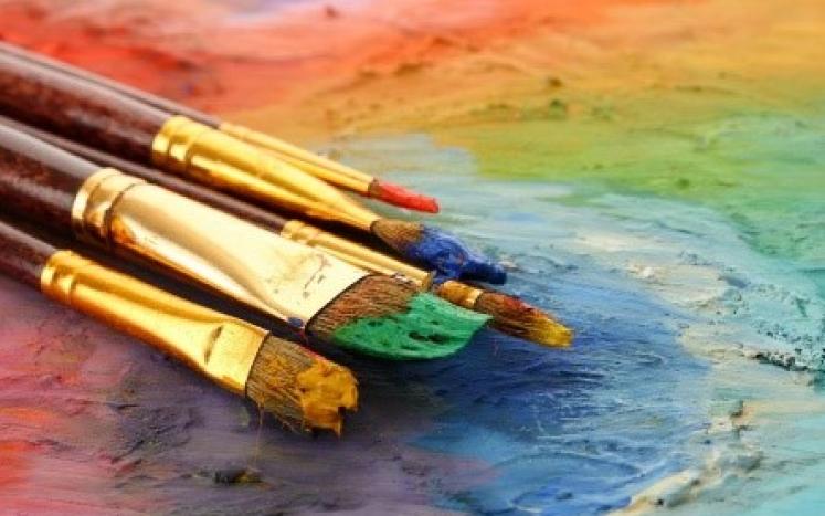 paintbrushes with paint on a colorful background
